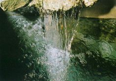 the water is running over the rocks into the pool at the bottom of the waterfall