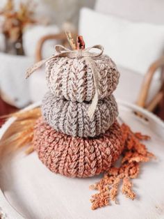 three knitted pumpkins are stacked on top of each other in front of a white chair