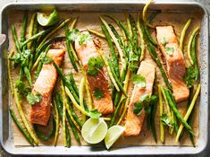 salmon, asparagus and green beans on a baking sheet with lime wedges