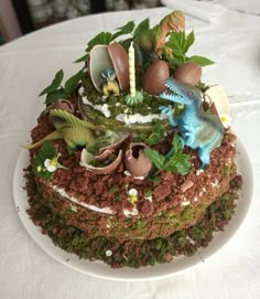 there is a cake that has dinosaurs on it and eggs in the grass around it