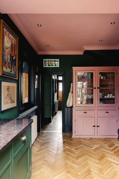 a room with green walls and wooden floors, painted in shades of pink and green