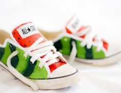 a pair of green and red sneakers with white laces on the bottom, sitting on a bed