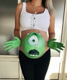 a pregnant woman wearing an ugly green monster belly cosplay with her hands out