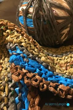 a ball of yarn sitting on top of a table next to a pile of knitted rugs