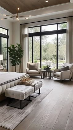 an elegant bedroom with large windows and wooden flooring is furnished in neutral colors, including beiges and browns