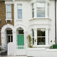 a white brick house with green door and window shutters on the front, in london