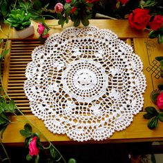 a white doily sitting on top of a wooden table next to flowers and potted plants