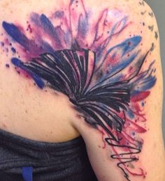 the back of a woman's shoulder with watercolor splashs on it