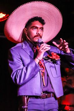 a man in a purple suit and sombrero holding a microphone