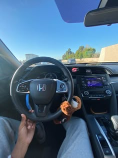 a person is sitting in the driver's seat of a car with a stuffed animal