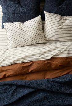 an unmade bed with blue and brown sheets