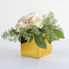 a yellow vase filled with white flowers and greenery