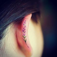 a woman's behind the ear tattoo with pink flowers on her left side piercing