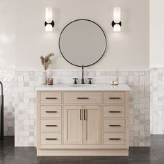 a bathroom with two sinks and a round mirror