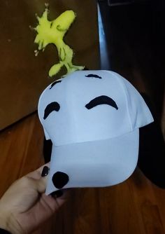 a person holding a paper hat with a face drawn on it