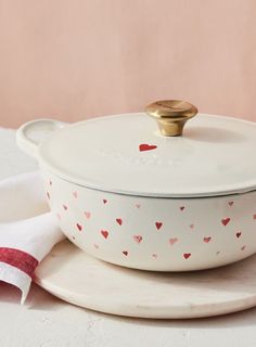 a white casserole dish with hearts on it and a red striped napkin next to it