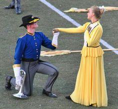 two people dressed in costume and holding hands with each other on the ground while one man is kneeling down