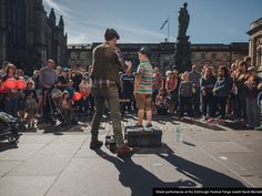 a man standing next to a little boy on top of a suitcase in front of a crowd