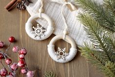 two white hoop earrings with snowflakes hanging from them on a table next to christmas decorations