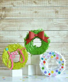 three paper wreaths with bows on them sitting next to each other