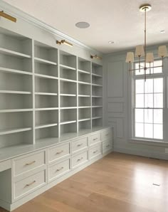 an empty room with white bookcases and wood floors