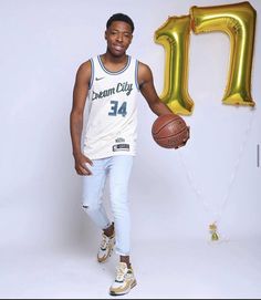 a man holding a basketball in front of the number one balloon