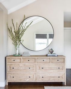 a large round mirror on the wall above a dresser