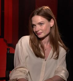 a woman sitting in a chair with her arms crossed and looking off to the side