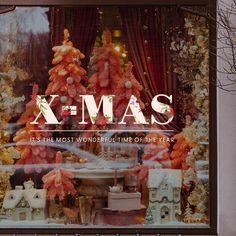 a store front window with christmas decorations and trees in the window, which reads x - mas it's the most wonderful time of the year