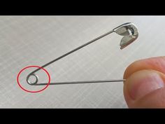 someone is holding the end of a metal pin with a red circle on it's side