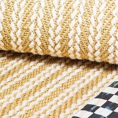 an up close shot of the fabric on a checkerboard flooring pattern in gold, white and black