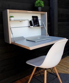 a laptop computer sitting on top of a desk next to a white chair and shelf