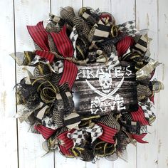 a pirates wreath on a white wooden wall with red and black ribbon around the edges