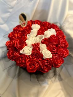 red and white roses arranged in the shape of a heart on top of a bed