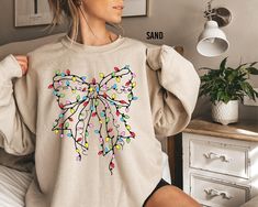 Christmas Light Coquette Bow Sweatshirt, Christmas Sweatshirt, Christmas Light Tee, Christmas Season Shirts, Holiday Sweater, Christmas Gift Thank you for shopping with us❤️ Size - Our products are unisex fit - You can check our size and color charts on our listing photos. How To Order - Select a size - Select a t-shirt color - If available, indicate the design (text) color in the personalization box - Click add to cart. You can go back to add more shirts. - Click "Proceed to check out". Care Instruction -Machine wash in cold water -Do not use bleach -Tumble dry low -Inside out, wash with delicate cycle -Do not iron directly over design Production and Shipping - Processing is 1-3 days * Shipping Time is depending on the shipping option that you choose during to checkout process - Please co Light Coquette, Bow Sweatshirt, Christmas Coquette, Light Girls, Bow Sweater, Design Text, Coquette Bow, Sweatshirt Christmas, Christmas Light