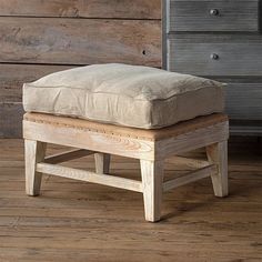 a wooden foot stool sitting on top of a hard wood floor next to a dresser