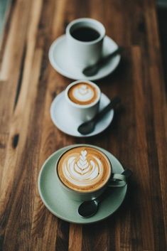 two cups of coffee sitting on top of a wooden table