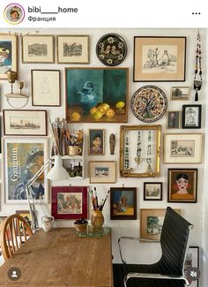 a dining room table surrounded by many framed pictures and other art work on the wall