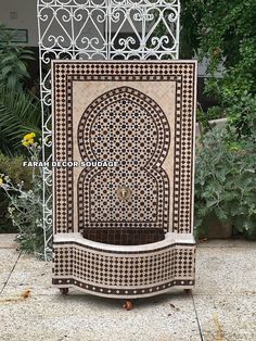 an intricately designed fountain sits in the middle of a patio area with plants around it