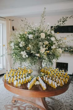 a table topped with lots of small yellow and white candy bars next to a vase filled with flowers