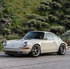 an old white porsche parked on the side of the road