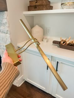 a person holding a large metal object in their hand near a shelf with other items on it