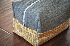 a gray and yellow bag sitting on top of a wooden floor