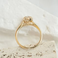 a yellow gold engagement ring with a diamond on it's shants, resting on a rock