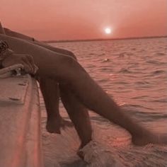 a woman sitting on the edge of a boat at sunset