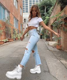 a woman wearing ripped jeans and white sneakers