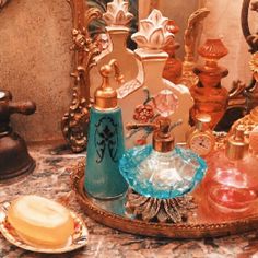 an assortment of perfume bottles sitting on top of a table next to a mirror and soap dispenser