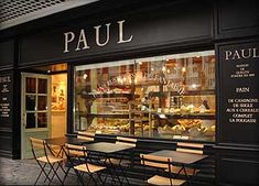 an outside view of a restaurant with tables and chairs in front of the storefront