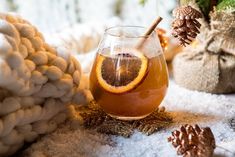 a glass filled with liquid sitting on top of a table next to a pile of pine cones