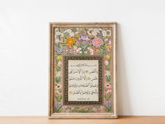 an ornate framed painting on a wall with flowers and arabic writing in the middle frame